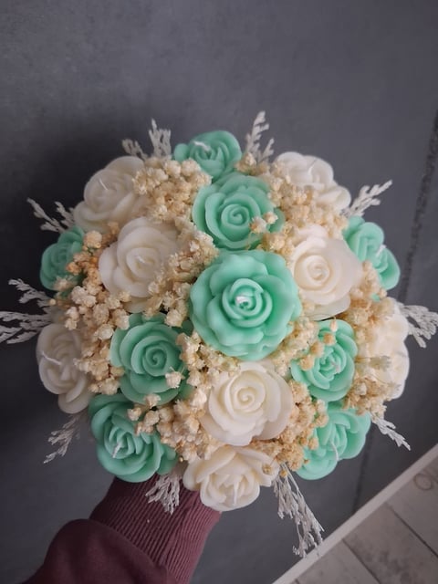 Decorative bouquet with mint green, white, and cream-colored clay roses with dried grasses and small filler flowers, tied with burgundy ribbon